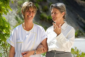 Nurse and resident strolling outside on a sunny day